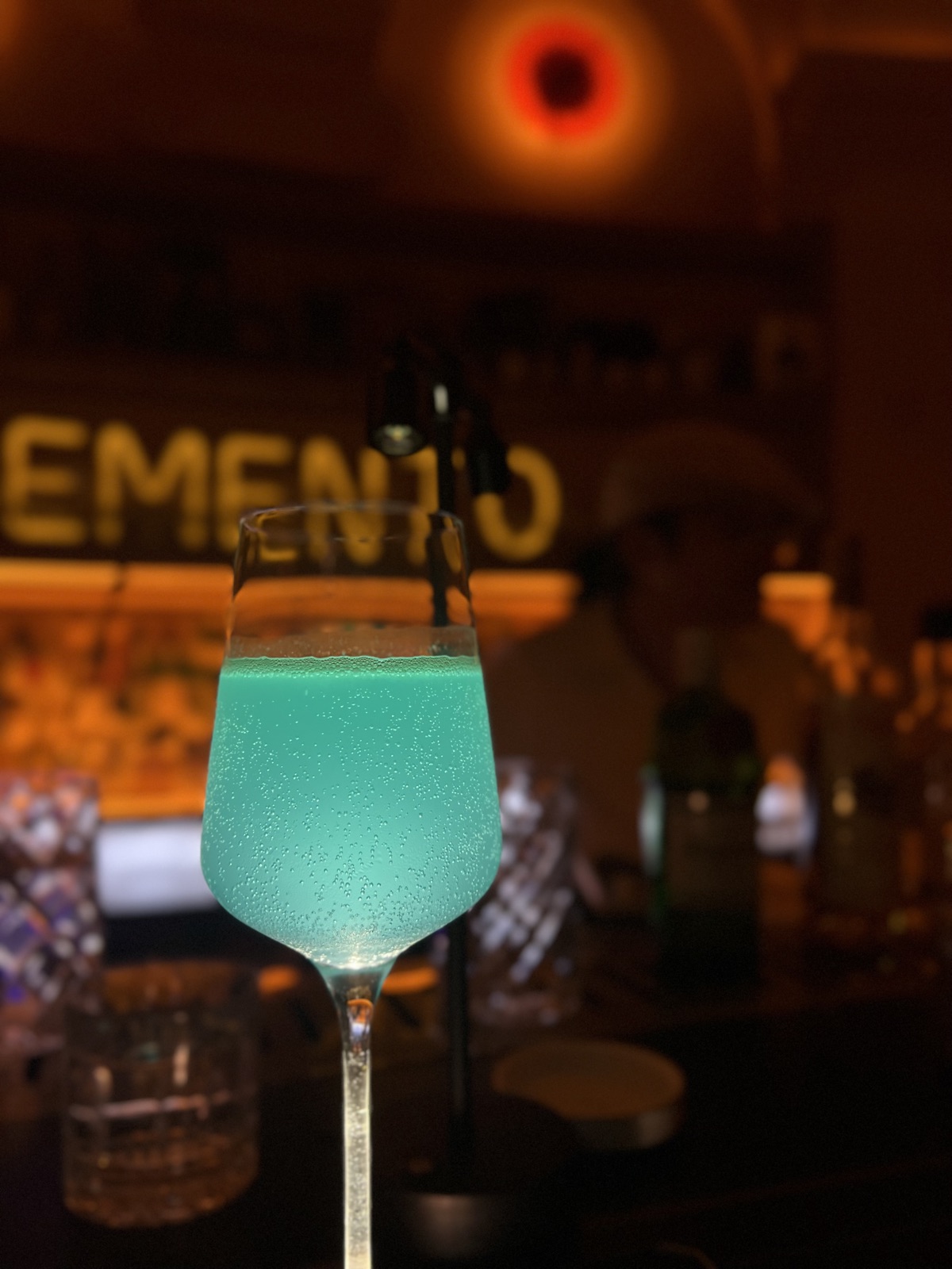 A vibrant blue cocktail in a glass at a bar, representing a moment of reflection on past trauma and life struggles.